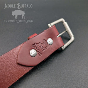 Close-up of Burgundy latigo leather belt underside with Chicago screws, buckle, and Noble Buffalo stamp