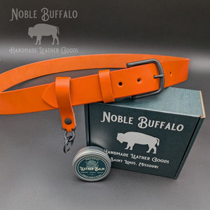 Carrot orange English Bridle leather belt displayed with leather keychain, balm and Noble Buffalo gift box