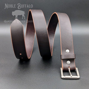 Dark brown Horween Illini Latigo leather belt arranged in waves, showing contrasting tan edges, a leather keeper, and silver-tone buckle.