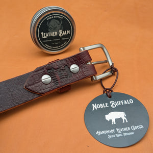 Close-up of Dark Cherry alligator-embossed leather belt buckle, maker’s stamp, and leather balm