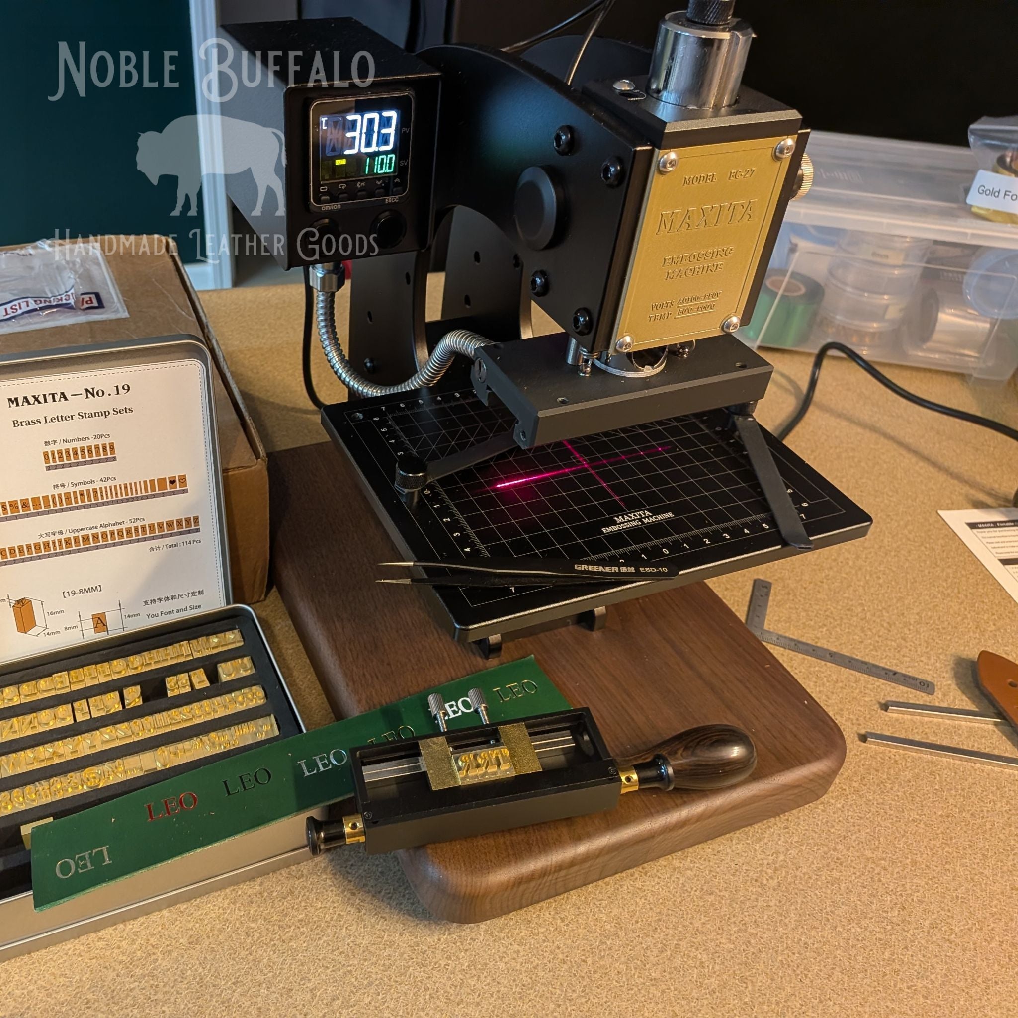 Leather embossing machine with brass letter stamps used to personalize Noble Buffalo leather belts with initials.