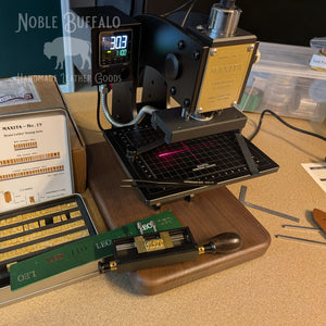 Leather embossing machine with brass letter stamps used to personalize Noble Buffalo leather belts with initials.