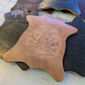 Close-up of handmade full grain leather drink coaster with embossed jackalope design, American made leather goods with smooth finish and durability