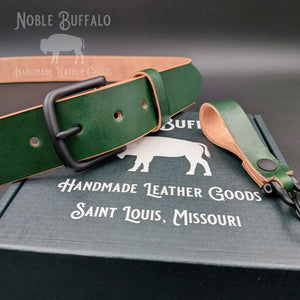 Noble Green Hermann Oak Latigo belt with a black buckle and matching green leather keychain displayed on a Noble Buffalo box.